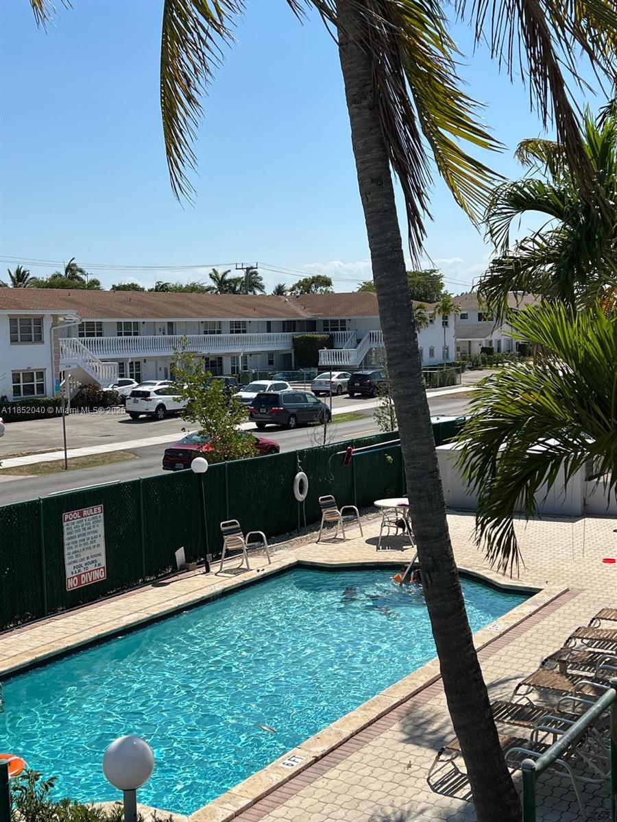 2175 Northeast 56th Street, Unit 211 Fort Lauderdale, FL 33308 - Photo 4 of 15 a view of a swimming pool with a lawn chairs under an umbrella