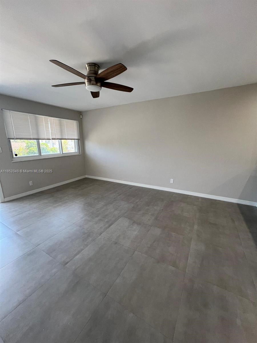 2175 Northeast 56th Street, Unit 211 Fort Lauderdale, FL 33308 - Photo 6 of 15 an empty room with windows and ceiling fan