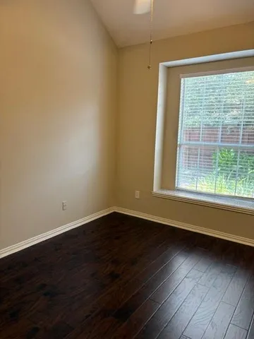 a view of an empty room with wooden floor and a window