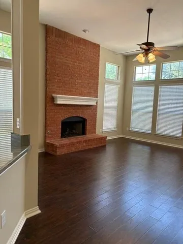 a view of wooden floor fire place and windows in a room