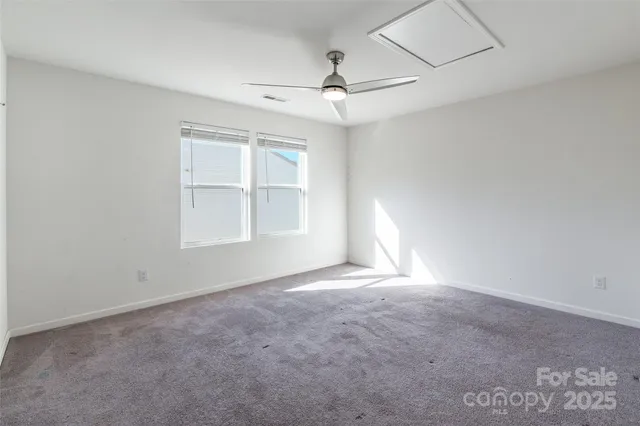 an empty room with windows and chandelier fan