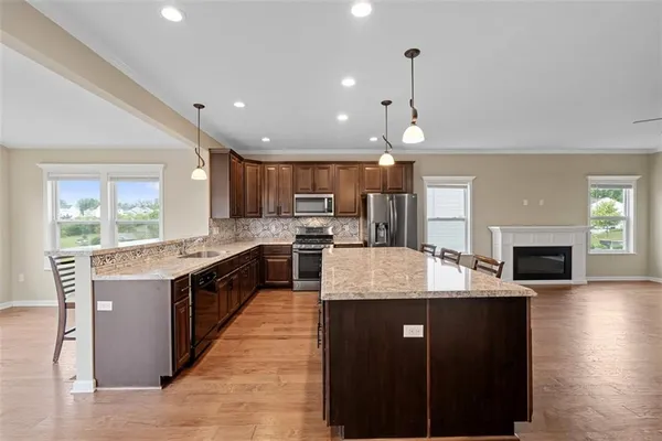 a large kitchen with kitchen island a sink dishwasher stove and white cabinets with wooden floor
