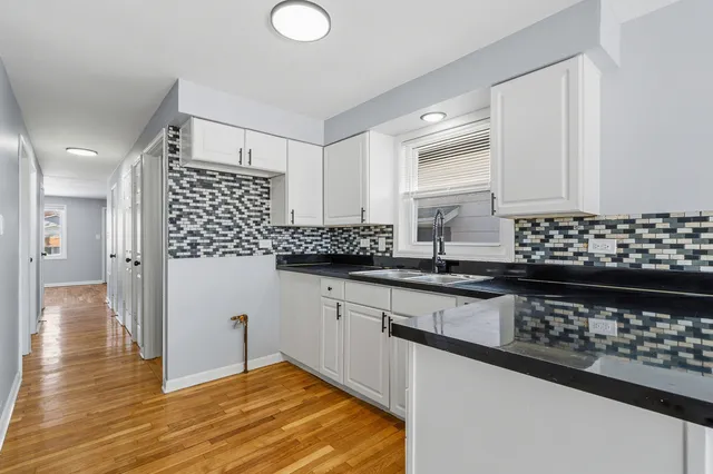 a kitchen with granite countertop a stove a sink dishwasher and a refrigerator with wooden floor