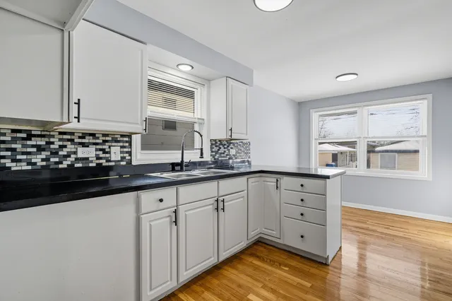 a kitchen with granite countertop a sink cabinets and wooden floor