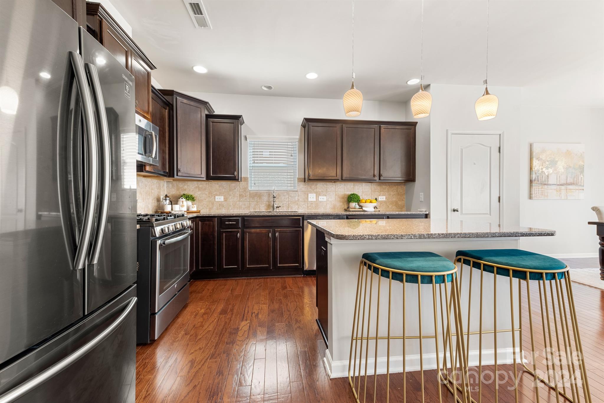1555 Spring Blossom Trail Fort Mill, SC 29708 - Photo 8 of 47 a kitchen with stainless steel appliances granite countertop a refrigerator a sink dishwasher a stove and white cabinets with wooden floor