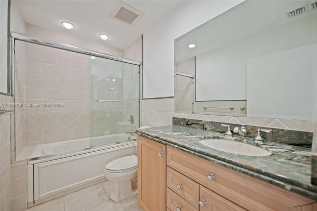a bathroom with a granite countertop sink a toilet and shower