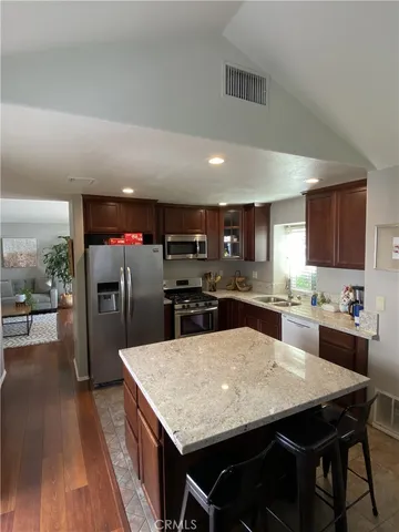 a kitchen with stainless steel appliances kitchen island granite countertop a kitchen island a cabinets a sink and a refrigerator