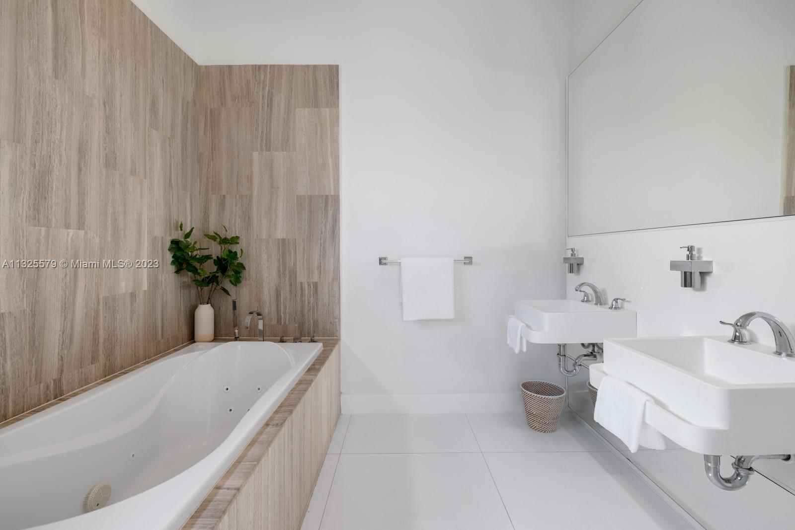6050 La Gorce Drive Miami Beach, FL 33140 - Photo 12 of 31 a bathroom with a tub a sink and mirror