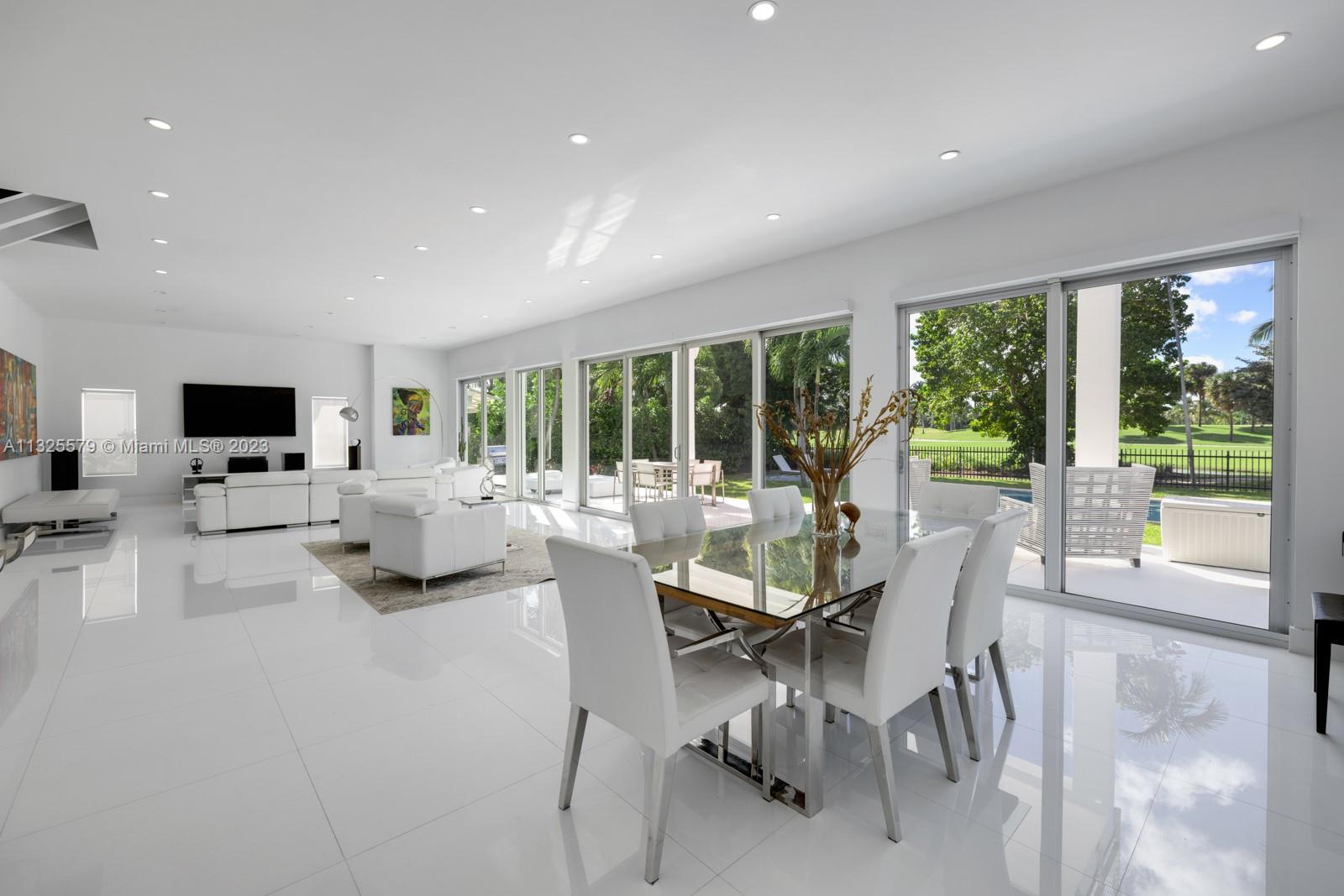 6050 La Gorce Drive Miami Beach, FL 33140 - Photo 3 of 31 a dining room with furniture a floor to ceiling window and an outdoor view