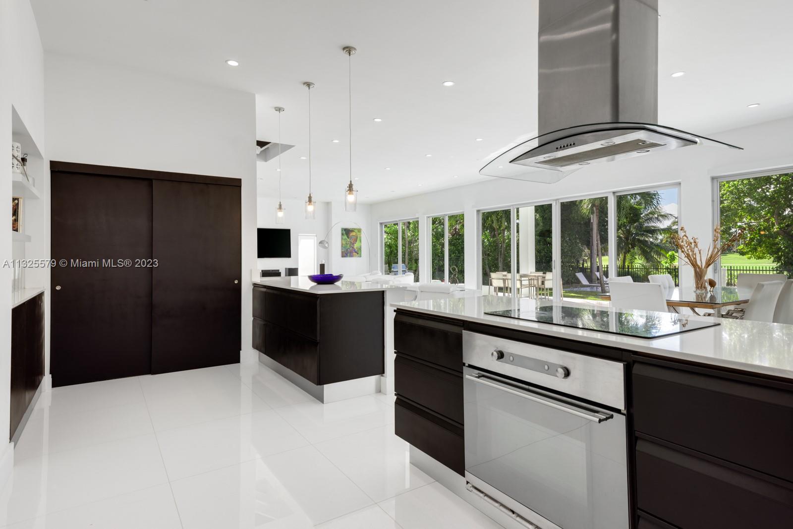 6050 La Gorce Drive Miami Beach, FL 33140 - Photo 5 of 31 a kitchen with stainless steel appliances kitchen island granite countertop a refrigerator and a sink