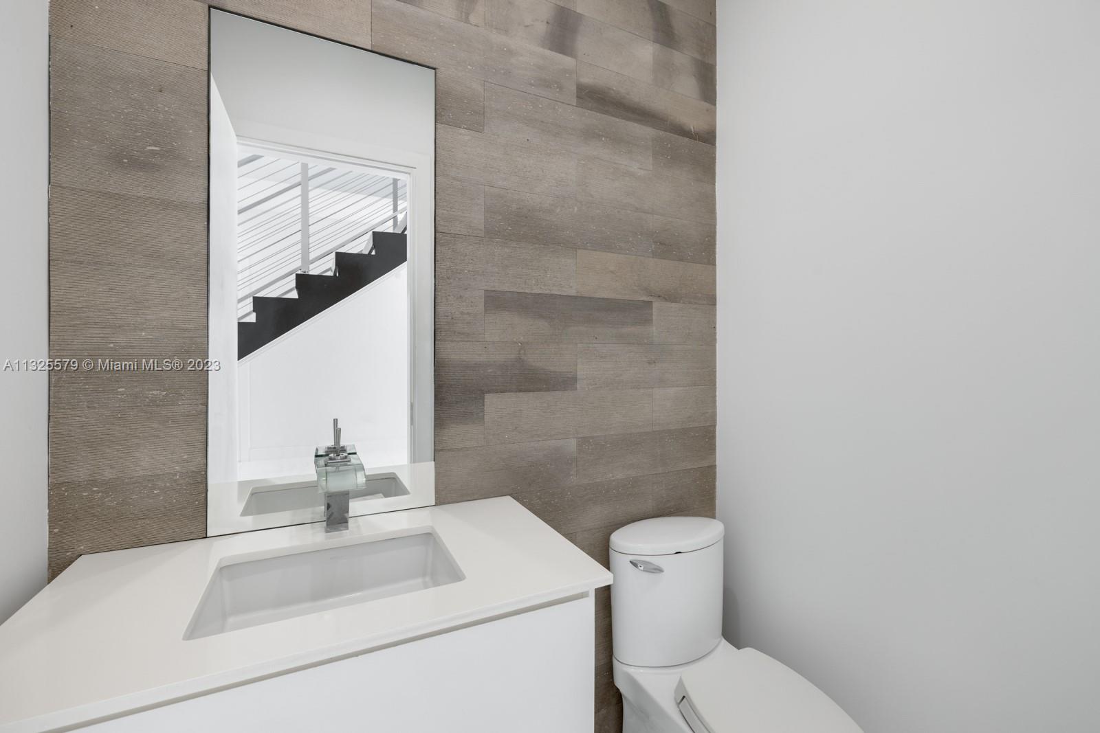 6050 La Gorce Drive Miami Beach, FL 33140 - Photo 10 of 31 a bathroom with a toilet sink and mirror