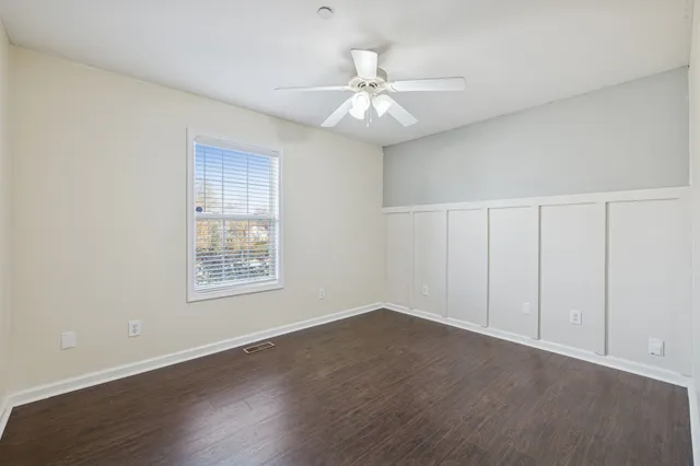 an empty room with wooden floor fan and windows