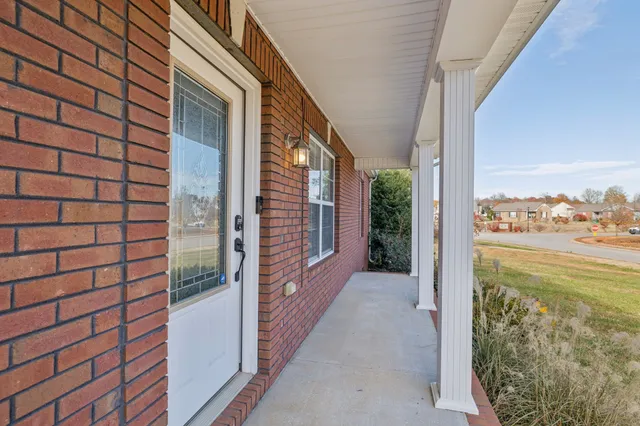 a view of an empty room with wooden floor and a ceiling fan
