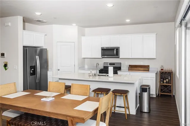 a kitchen with stainless steel appliances granite countertop a refrigerator a stove a sink a dining table and chairs