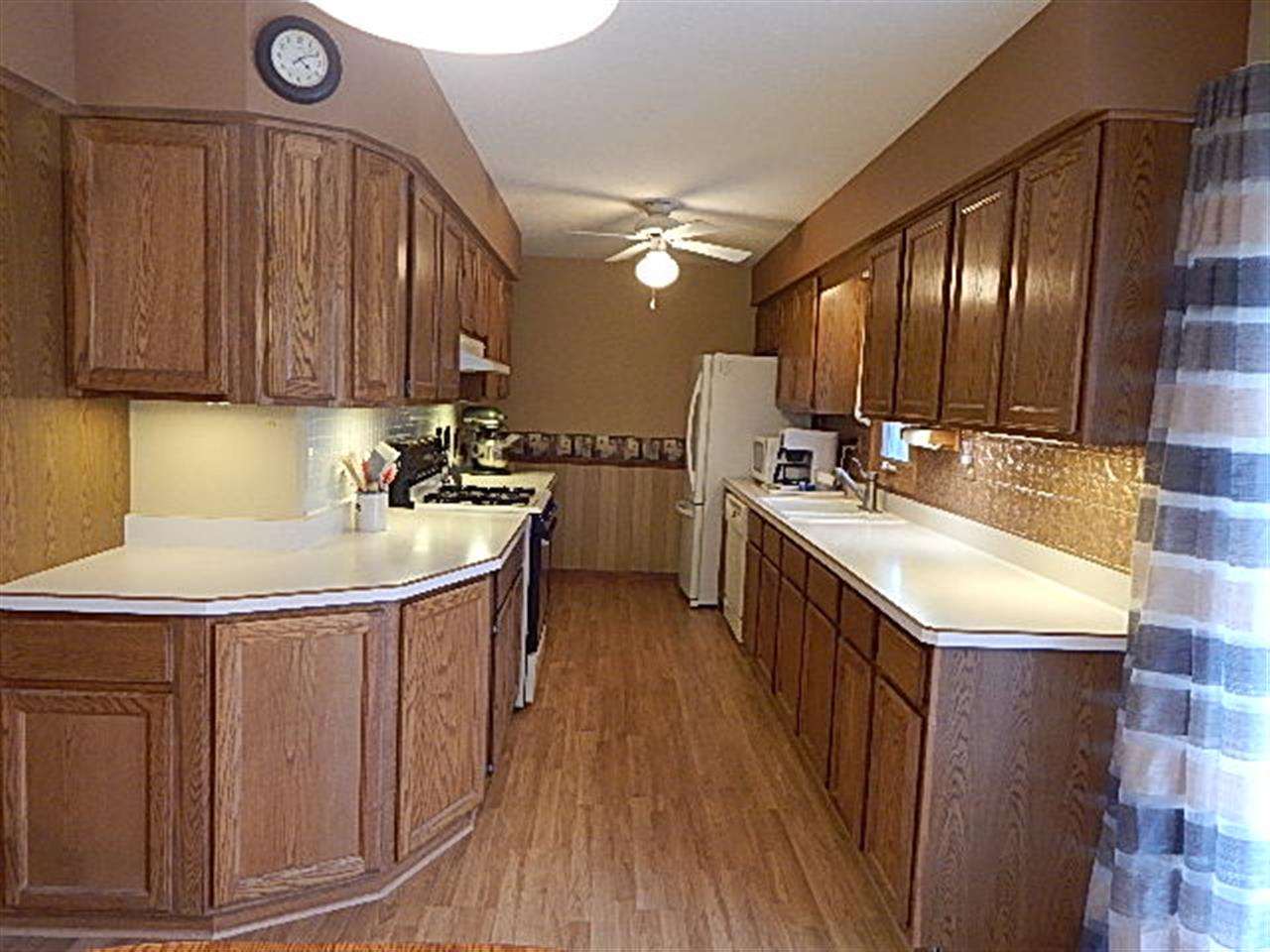 9925 Bitterroot Road Roscoe, IL 61073 - Photo 8 of 25 a kitchen with a sink a stove cabinets and wooden floor