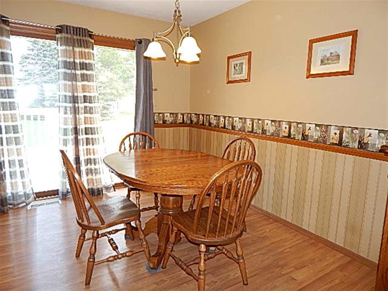 9925 Bitterroot Road Roscoe, IL 61073 - Photo 9 of 25 a dining room with furniture a chandelier and wooden floor
