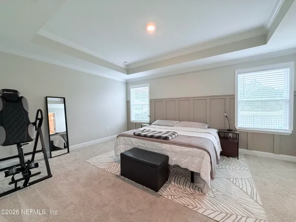 a bed sitting in a bedroom next to a window and a chair