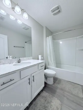 a bathroom with a toilet a sink a mirror and a bathtub