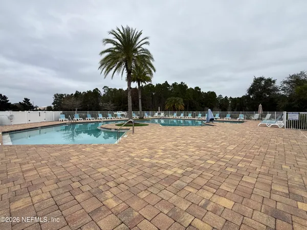 a view of swimming pool with a yard and palm trees