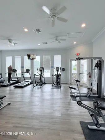a view of a room with gym equipment and wooden floor