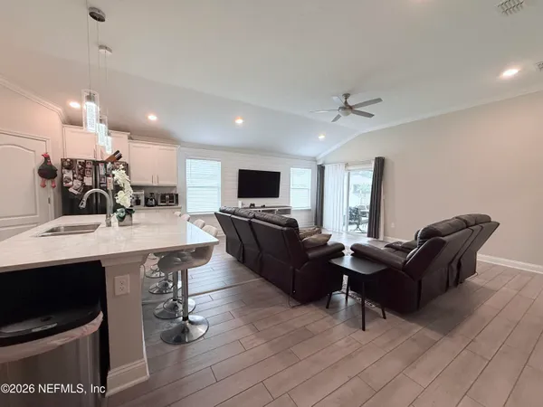 a living room with furniture a flat screen tv and kitchen view
