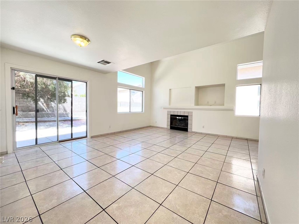 8284 West Rochelle Avenue Las Vegas, NV 89147 - Photo 2 of 29 A spacious living area features tiled flooring, a fireplace, and glass sliding doors leading to the outdoors.