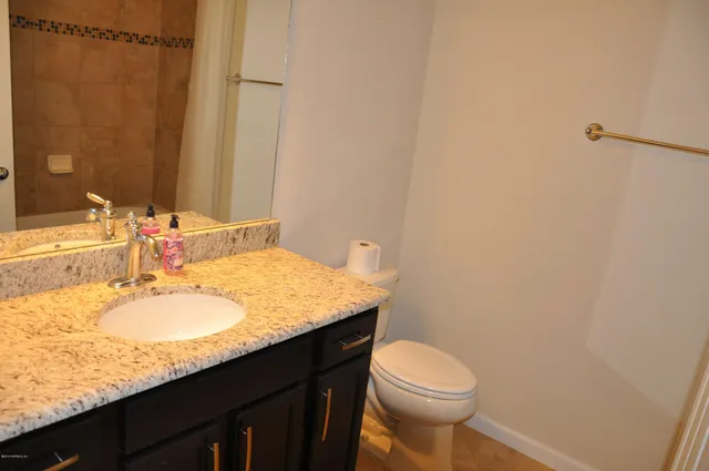 a bathroom with a granite countertop sink toilet and a mirror