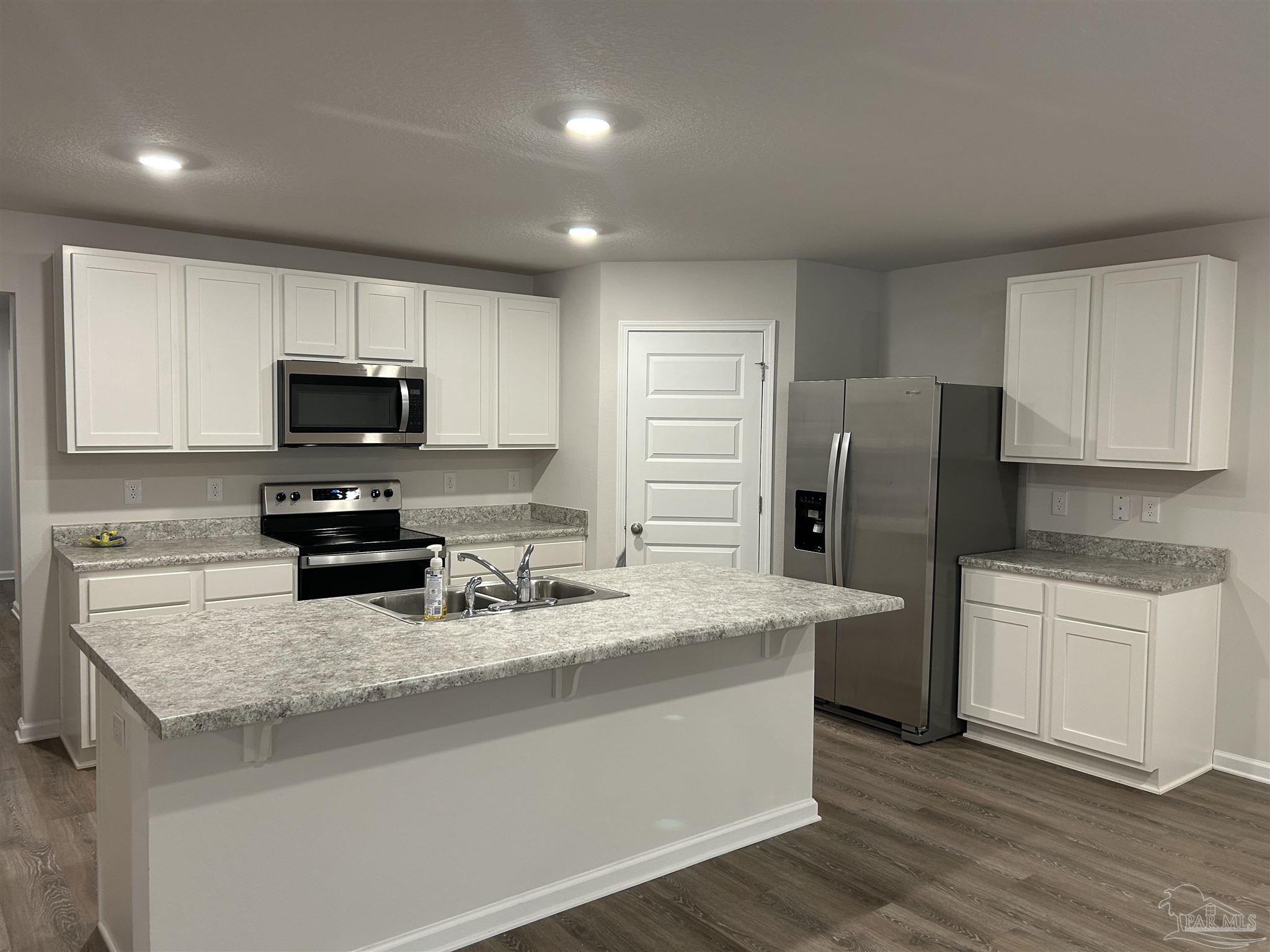 5351 Peach Drive Pace, FL 32571 - Photo 7 of 24 a kitchen with granite countertop a refrigerator and a stove top oven