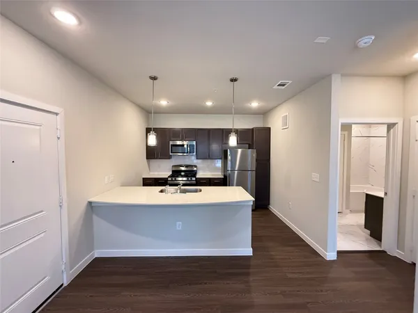 a view of kitchen with refrigerator stove and wooden floor