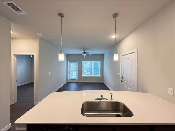 a kitchen with kitchen island a sink a counter top space and living room view