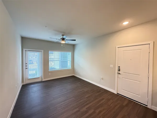 a view of an empty room with wooden floor and a window