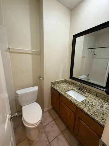 a bathroom with a granite countertop sink toilet and a mirror