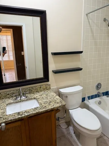 a bathroom with a granite countertop toilet sink and mirror