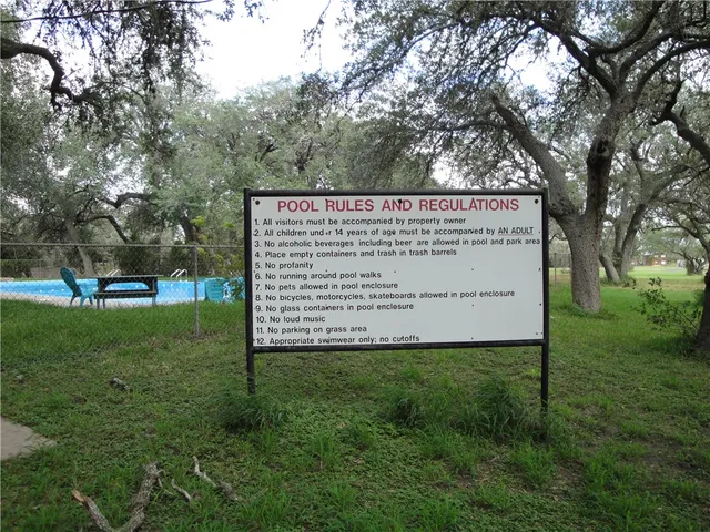 a view of a sign in a big yard with large trees