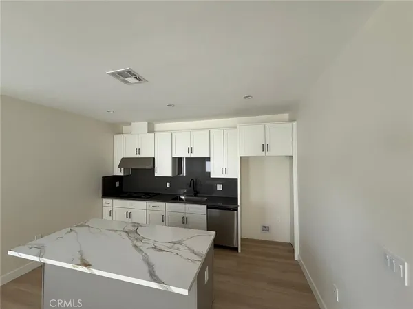 a kitchen with granite countertop white cabinets and refrigerator