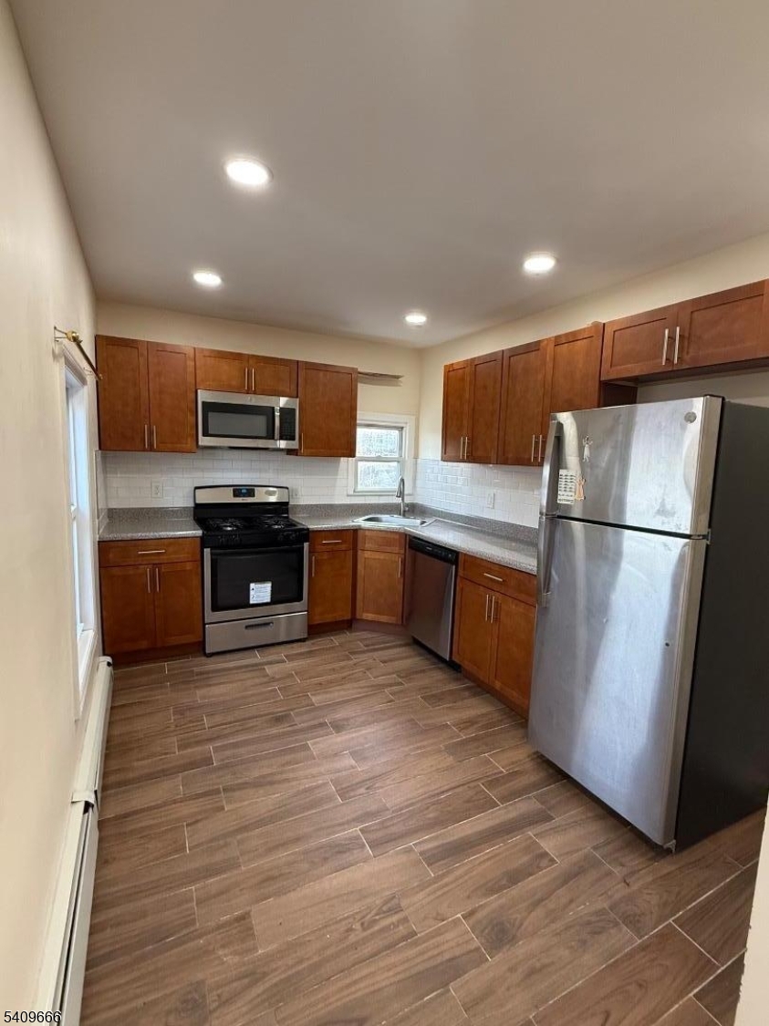 a kitchen with stainless steel appliances granite countertop a refrigerator a stove top oven a sink and dishwasher