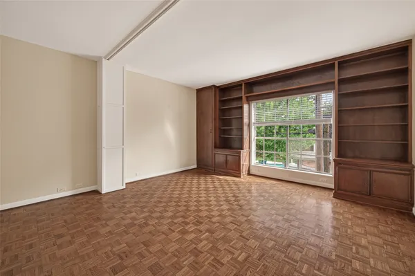 an empty room with chandelier fan and windows