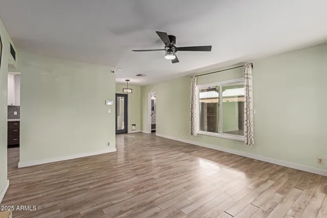 a view of an empty room with wooden floor and a window