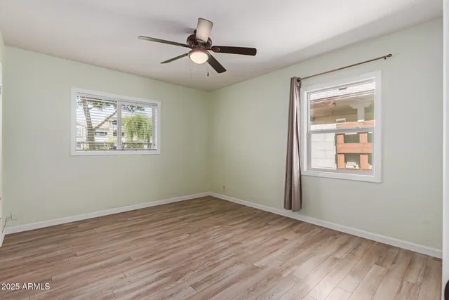 a view of empty room with wooden floor and fan