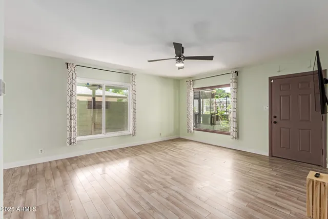 a view of an empty room with wooden floor and a window