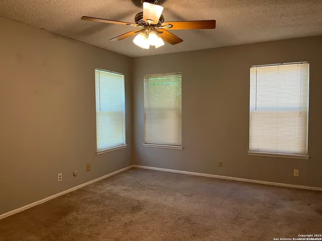 an empty room with windows and fan