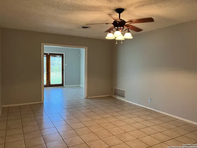 a view of an empty room with a chandelier fan