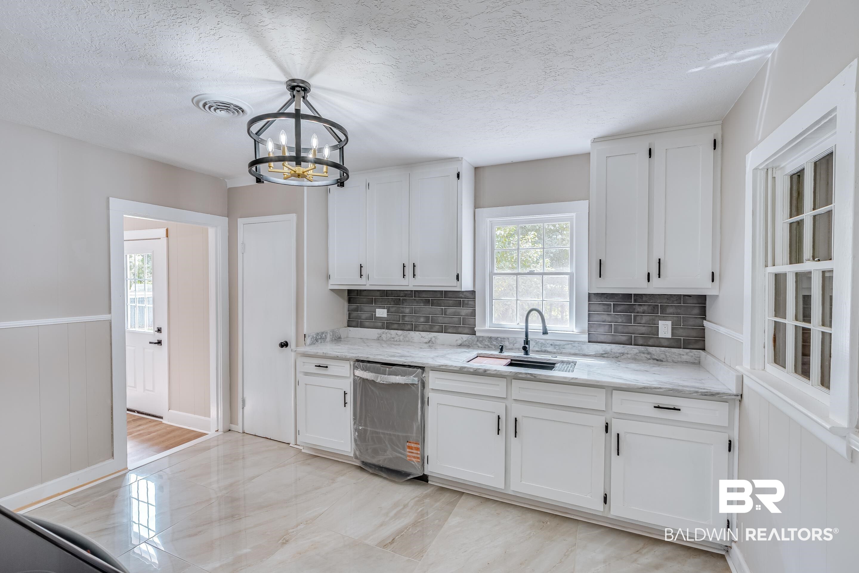 8001 16th Street Irvington, AL 36544 - Photo 11 of 35 Kitchen with white cabinetry, a wainscoted wall, dishwasher, pendant lighting, and a textured ceiling