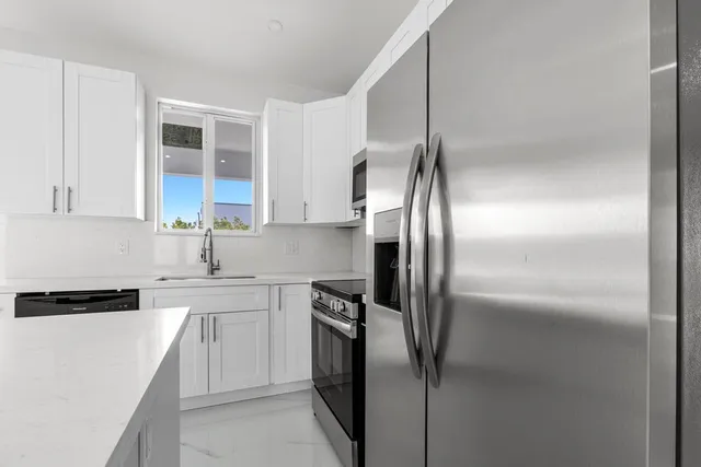 a metallic refrigerator freezer sitting inside of a kitchen