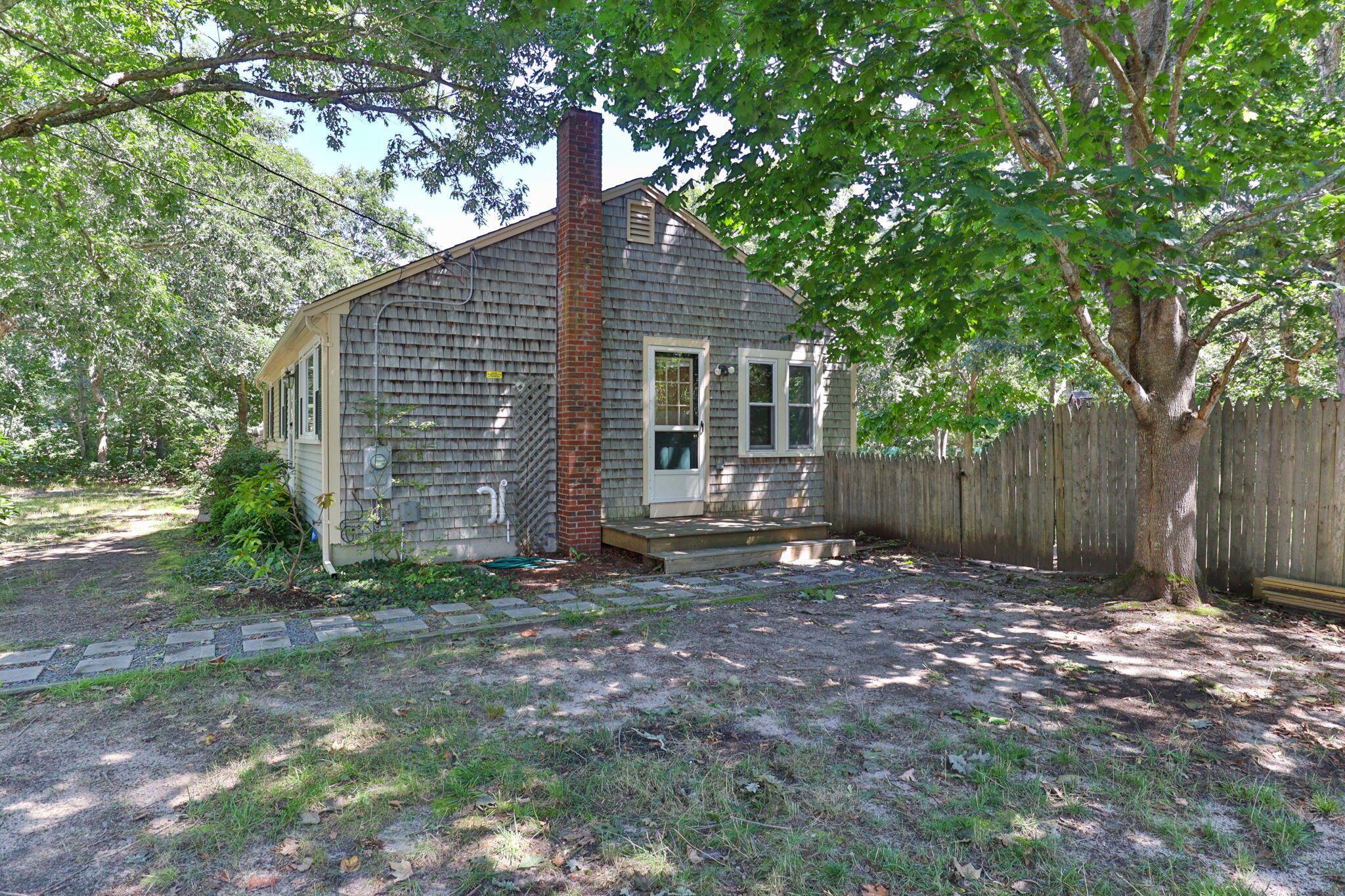 49 Russells Path Brewster, MA 02631 - Photo 29 of 37 a backyard of a house with large trees and wooden fence