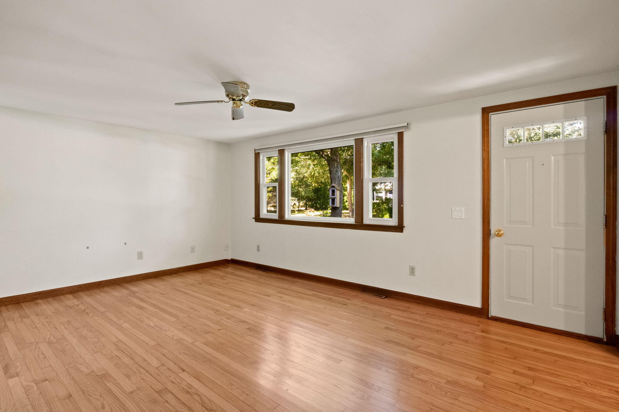 49 Russells Path Brewster, MA 02631 - Photo 7 of 37 an empty room with wooden floor chandelier fan and windows