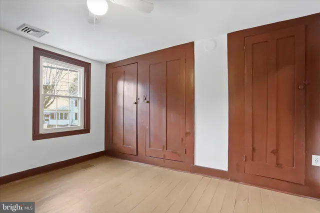 an empty room with closet and a ceiling fan
