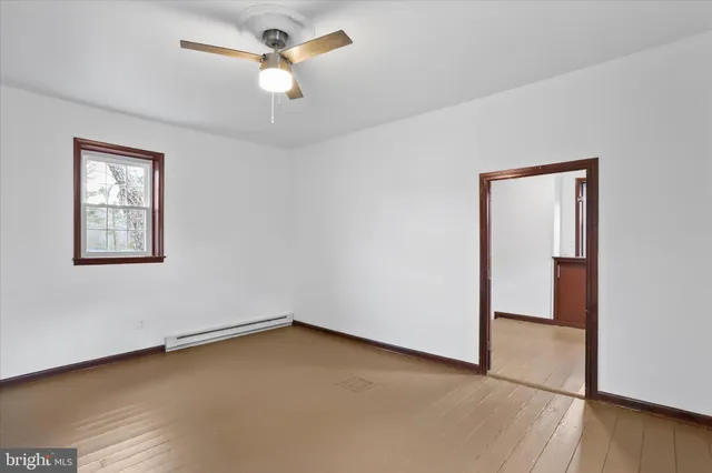 an empty room with wooden floor chandelier fan and windows