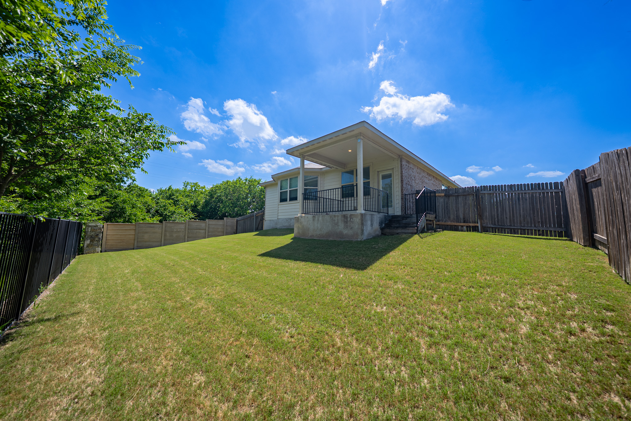 2508 Hat Bender Loop Round Rock, TX 78664 - Photo 21 of 22 Expansive backyard featuring a manicured lawn, a covered patio with columns and railing, and privacy fencing