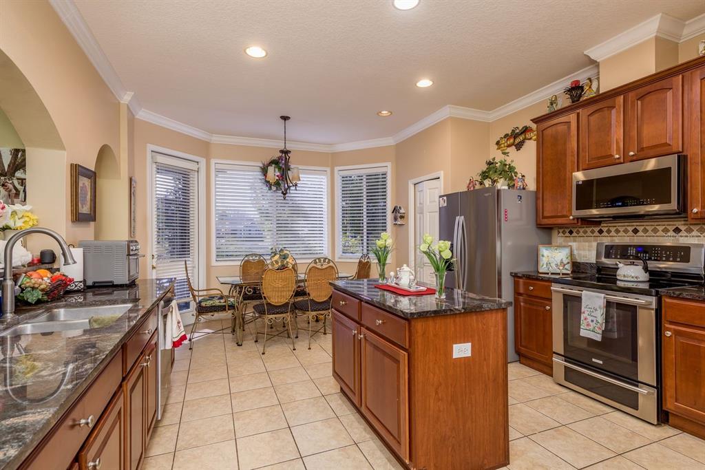19216 Inlet Cove Court Lutz, FL 33558 - Photo 12 of 41 a kitchen with stainless steel appliances granite countertop a stove top oven a sink dishwasher a dining table and chairs with wooden floor